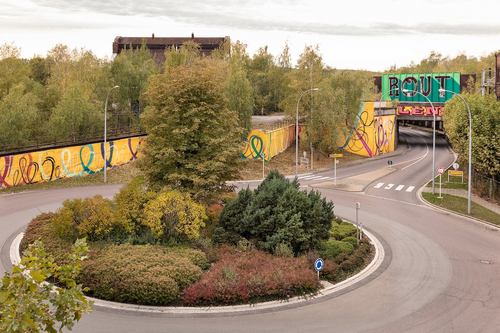 L’habillage de pont, par Sascha Di Giambattista, qui veut ancrer le nom de «Rout Lëns» dans l’imaginaire des gens, surplombe la fresque murale d’Eric Mangen, qui illustre l’idée de mouvement, de transformation et de transition. (Photo: Boris Loder)